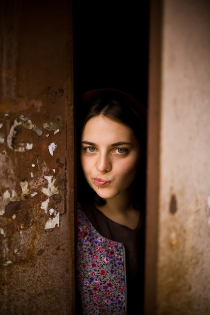 Foto una ragazza curiosa guarda da dietro la porta.