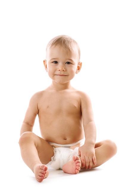 Foto ragazzino sano curioso in pannolino seduto e sorridente