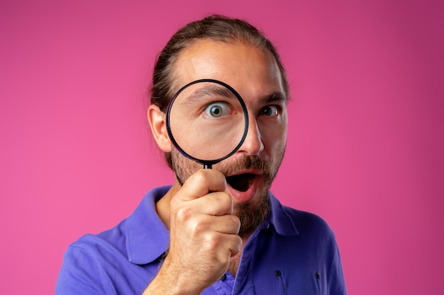 Curious hipster man looking through magnifying glass