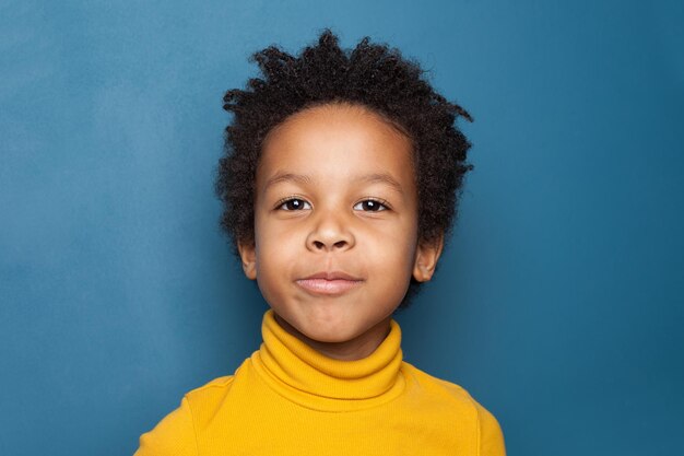 Портрет любопытного ребенка Счастливый маленький черный ребенок на синем фоне