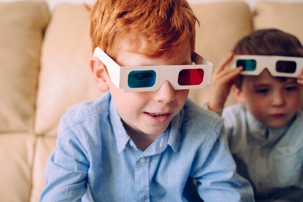 Curious little boy wearing three dimensional glasses and reading an interactive book at home.