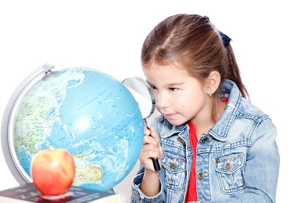 Curious little girl looking through magnifying glass on globe