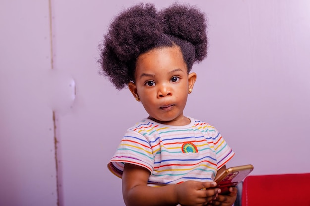 Любопытная маленькая девочка играет в игры на своем мобильном телефоне в помещении
