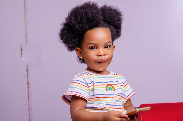 Curious little girl playing games on her mobile phone indoors