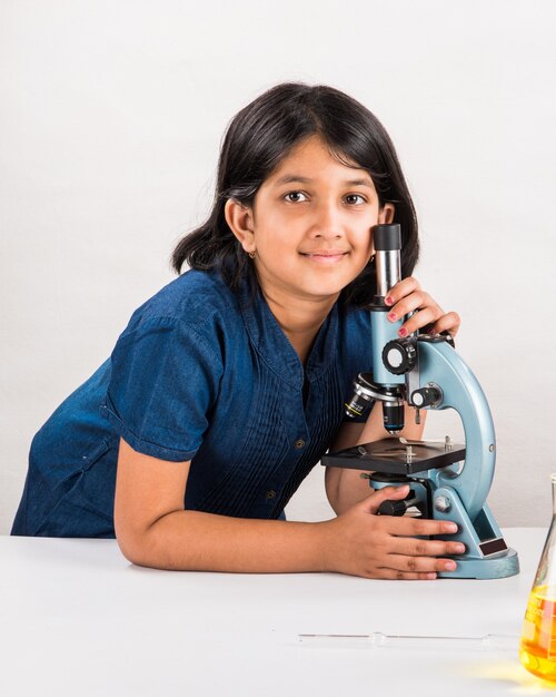 Curious little Indian school kids or scientists studying science, experimenting with chemicals or microscope at laboratory, selective focus