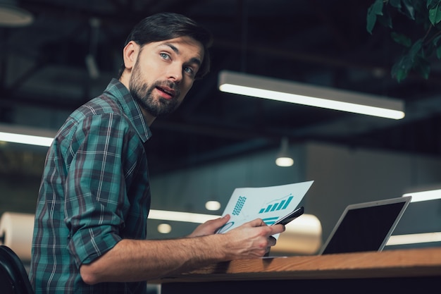 Curious man at the table working with graphics and turning back