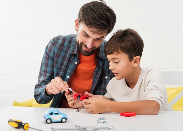 Curious son and father fixing toy cars