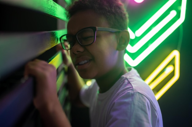 Curious teenage boy in eyeglasses looking through the gap in the wood slat wall