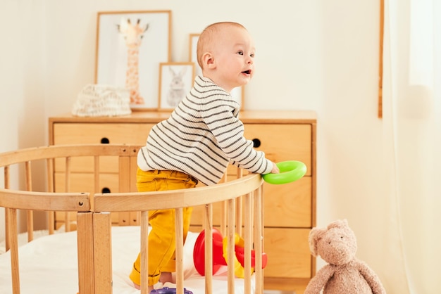 A curious toddler boy stands in the crib of the children's room