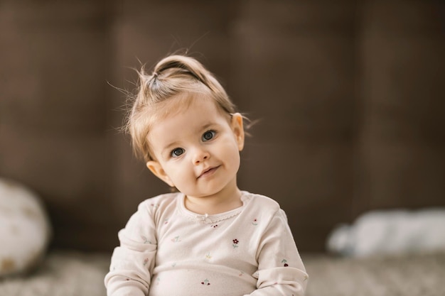 A curious toddler is looking at the camera with little smile