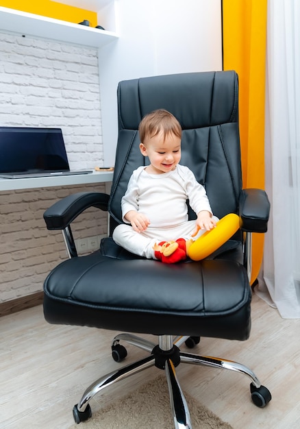 A Curious Toddler in a Sleek Modern Office Chair A small child sitting in a black office chair