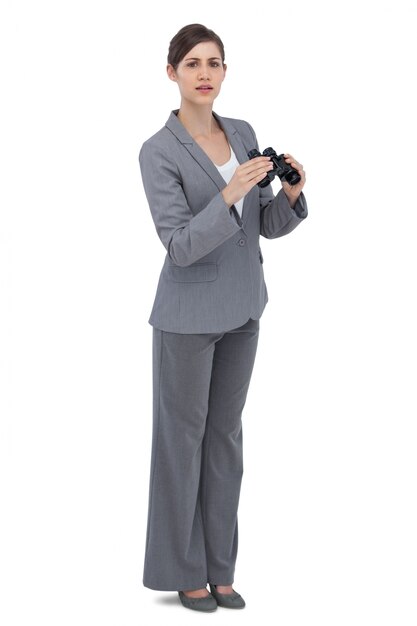 Curious young businesswoman posing with binoculars