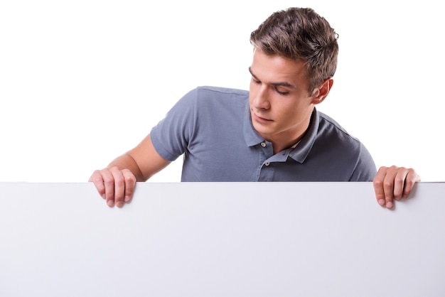 Curious young man. Handsome young man leaning at the copy space and looking at it