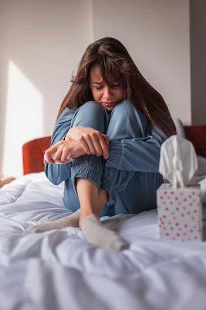 Curled up woman crying in bed