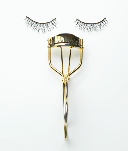 Curler and false eyelashes on white background