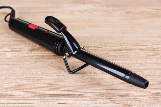 Curling iron on wooden background