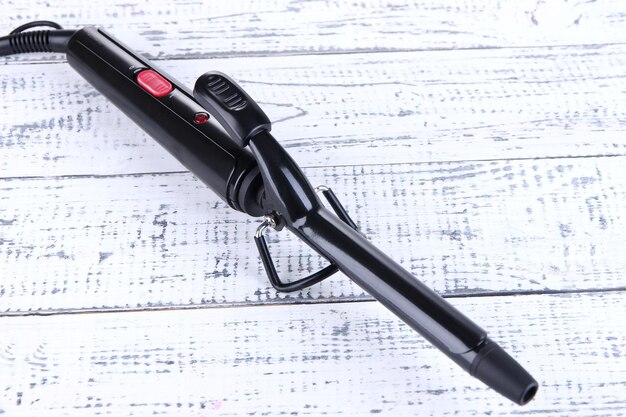 Curling iron on wooden background