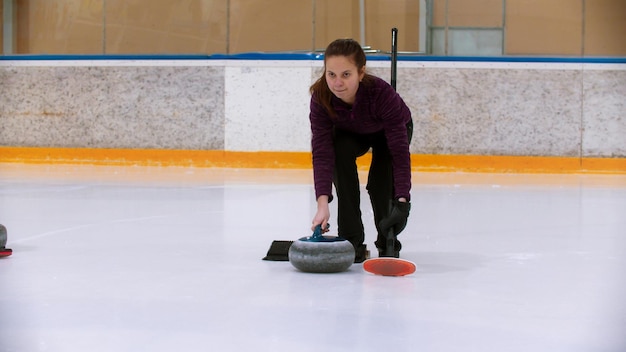 Formazione di curling sulla pista di pattinaggio una giovane donna sulla pista di pattinaggio