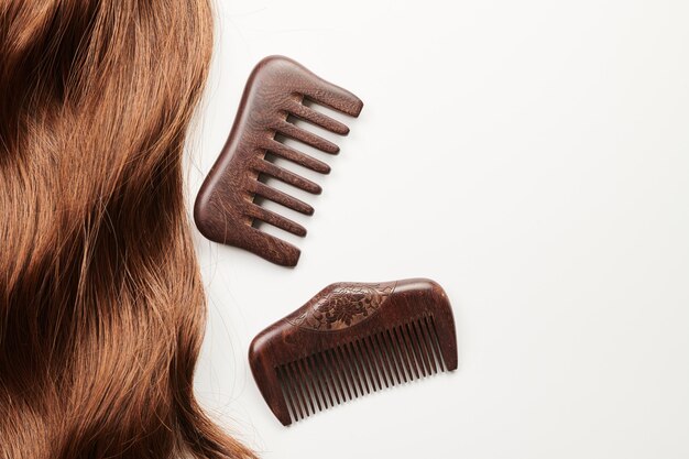 Curls of brown hair and a wooden comb on a white background hair care beauty salon concept