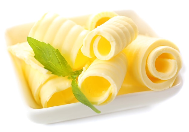 Curls of fresh butter with basil in bowl isolated on white