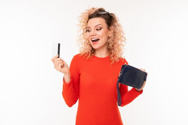 Curly blond girl with a credit card with a mockup and a handbag on white