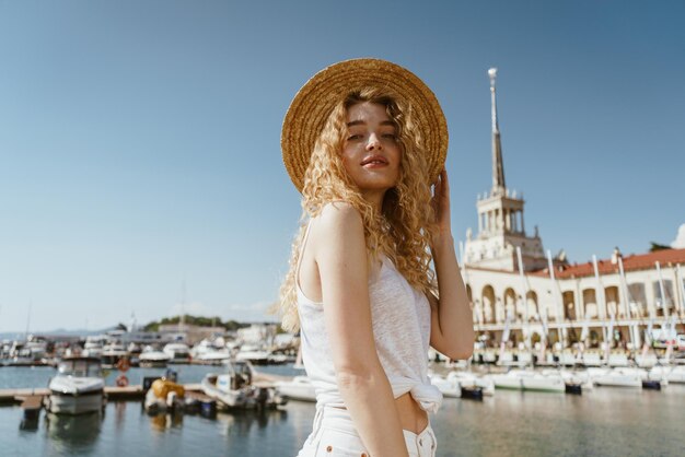 Curly blonde looks down at the camera on the background of the sea and boats