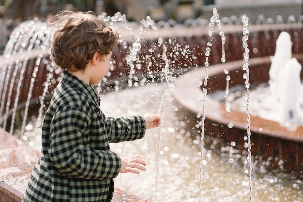 Curly boy playing at the fountain