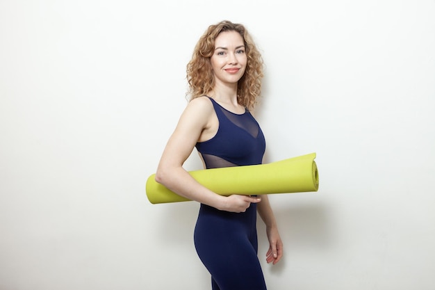 Curly Caucasian woman yogi with mat on white background