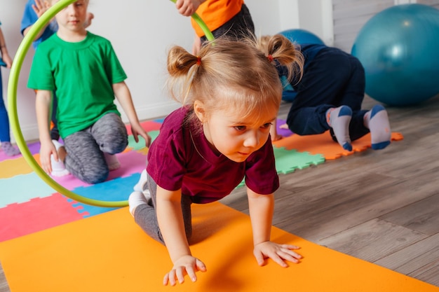 Curly girl crawling on colorful floor through hula hoops