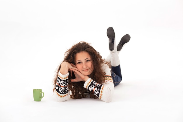 Curly girl in a knitted sweater lies on a white background copyspace