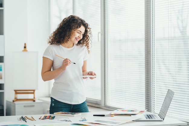 The curly girl with a brush drawing pictures on the table