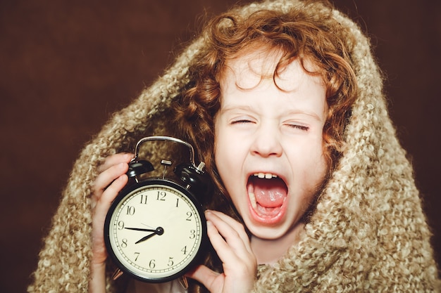 Curly girl  yawn and holding alarm clock.