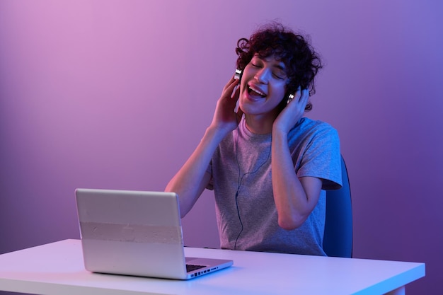 Curly guy sitting at the table gaming laptop lifestyle\
technology