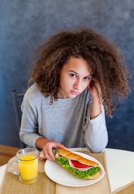 家で朝食をしているカーリーヘアティーンの女の子