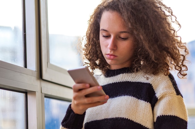 Curly hair teen girl using mobile phone