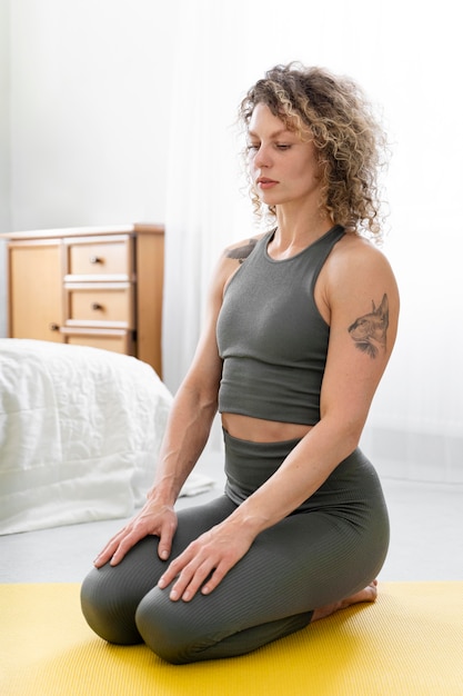 Curly-haired blonde vrouw doet yoga thuis