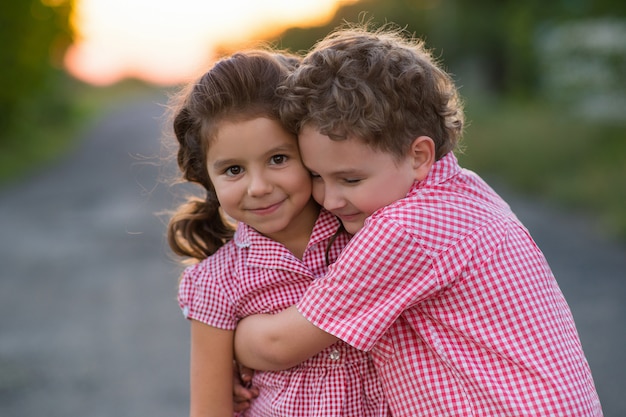 Foto una ragazza dai capelli ricci è abbracciata da un ragazzo dai capelli ricci. bambini vestiti nello stesso stile