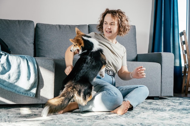 Donna scalza allegra dai capelli ricci con cane corgi addestramento all'obbedienza alimentazione animale seduta e gioco