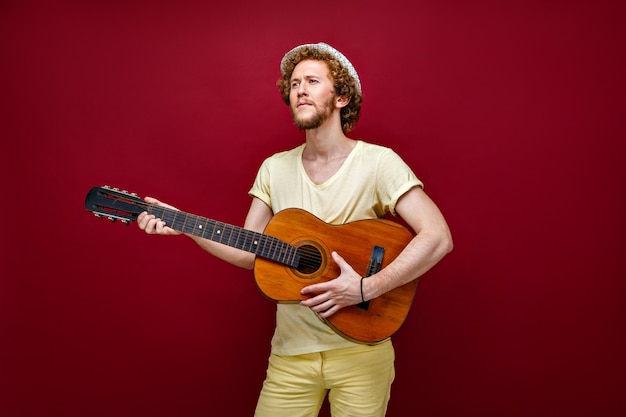 Curly-haired man in hat playing guitar