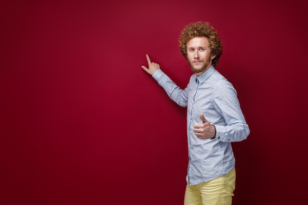 Curly-haired man in shirt met lege ruimte met wijsvinger