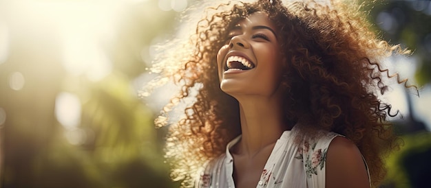 Curly haired young woman laughing outdoors in a sunny park afternoon