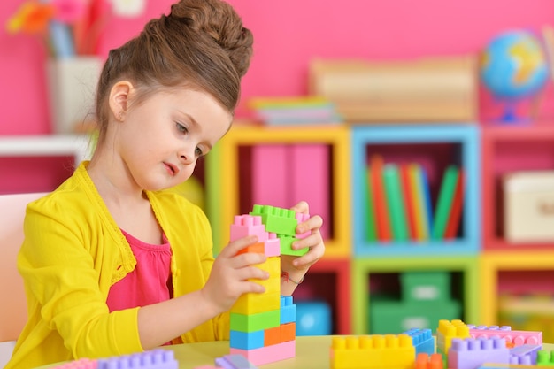 Curly little girl playing with colorful plastic blocks