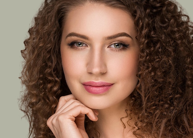 Curly long brunette hair young  woman touching face beauty  female portrait. Color backgound green
