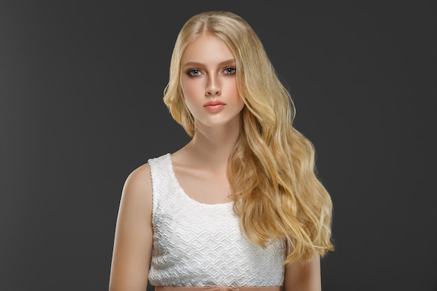 Curly long hair blonde young model. Beauty girl with curly perfect hairstyle. Studio shot.