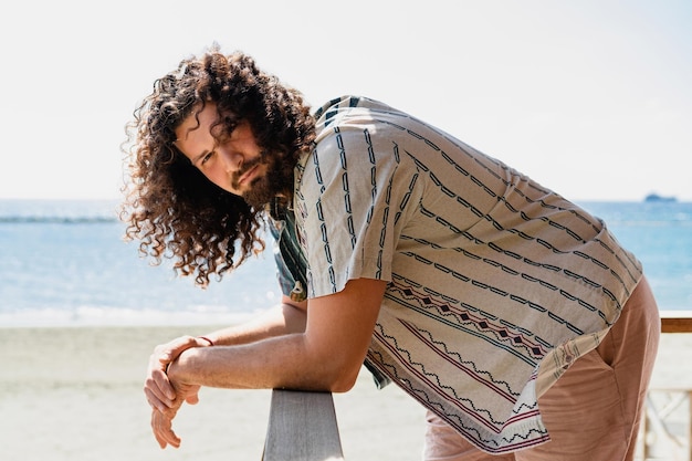 Curly man ontspannen op het strand tijdens zonnige zomerdag