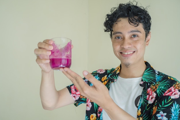 Curly man wear beachwear Hold a glass dragon fruit juice with smile and thirsty pose