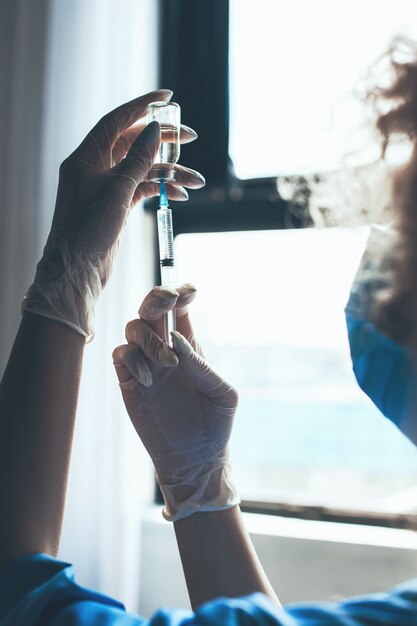 Curly nurse holding in hand a bottle with vaccine vaccination concept