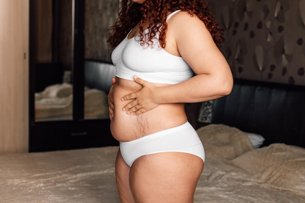 https://img.freepik.com/premium-photo/curly-plus-size-woman-white-underwear-standing-near-bed-bedroom-touching-stomach-with-stretch-marks-closeup-side-view-fat-burning-treatment-thick-belly-weight-loss-program-dieting_248570-4490.jpg?size=626&ext=jpg