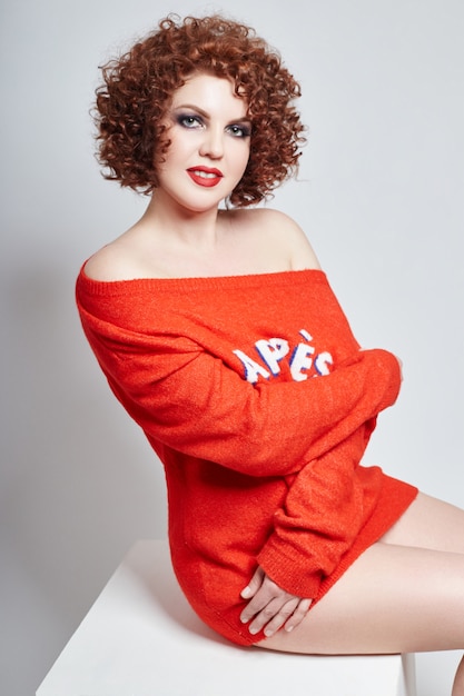 Curly redhead adult sexy woman in red sweater