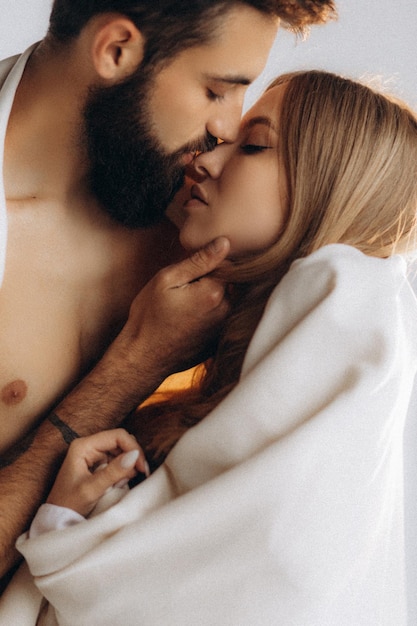 curly smiling woman hugging shirtless muscular boyfriend near christmas tree at home